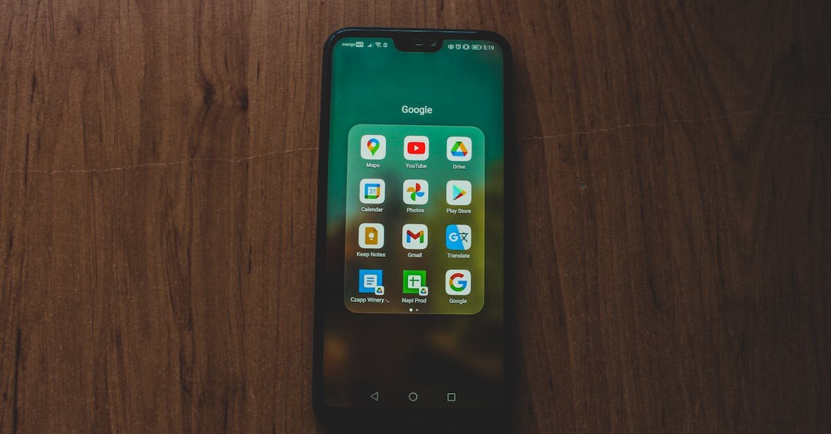 A smartphone showcasing various Google apps on a wooden table.